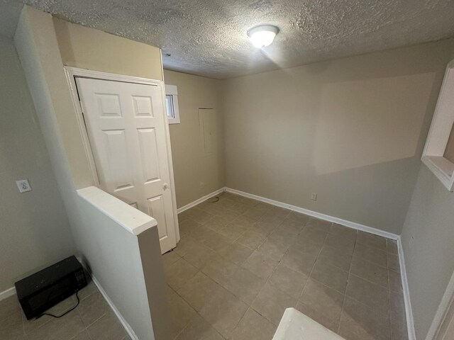 hallway featuring tile patterned floors and a textured ceiling