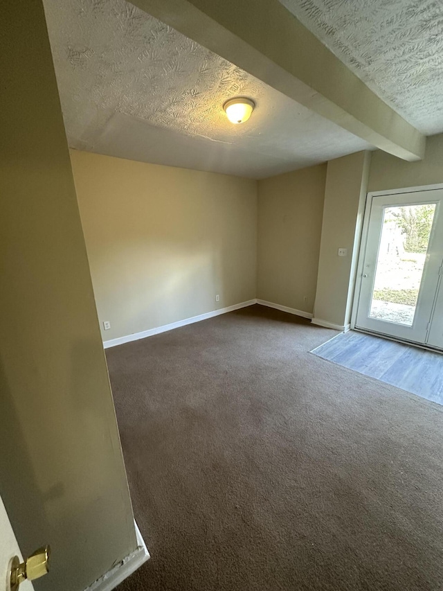 spare room featuring dark carpet and a textured ceiling