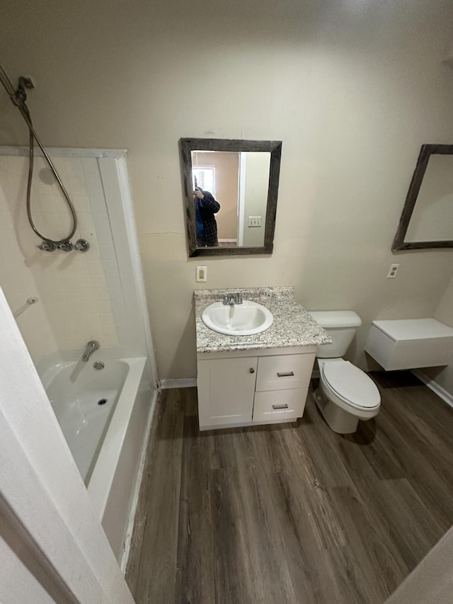 bathroom with baseboards, wood finished floors, toilet, and vanity