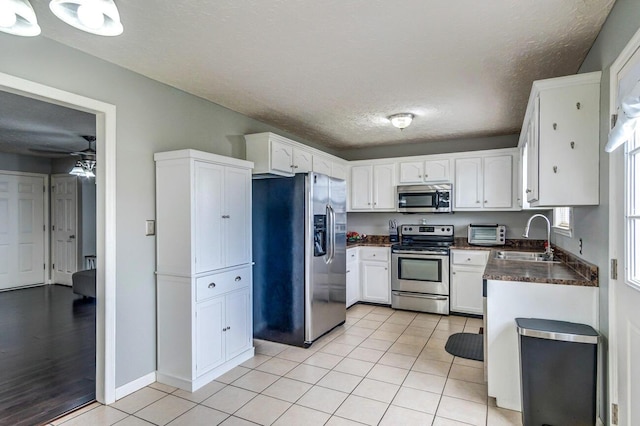 kitchen with white cabinets, appliances with stainless steel finishes, light tile patterned floors, and sink