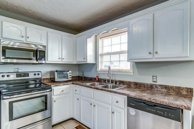 kitchen featuring white cabinets, appliances with stainless steel finishes, light tile patterned floors, and sink