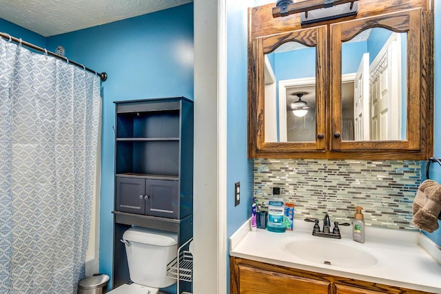 bathroom with decorative backsplash, toilet, a textured ceiling, and vanity