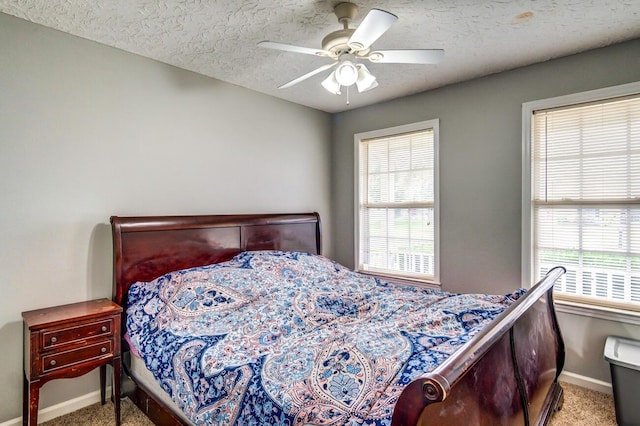 carpeted bedroom featuring ceiling fan and a textured ceiling