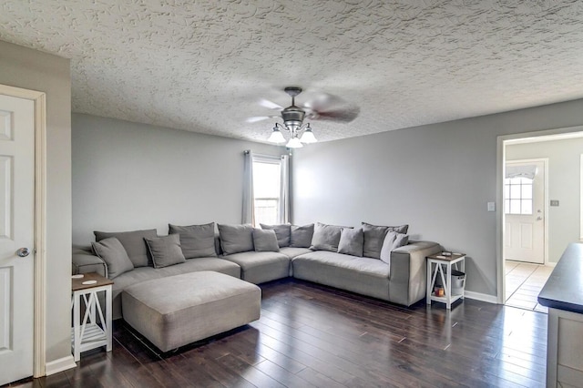 living room featuring a textured ceiling, ceiling fan, and dark wood-type flooring