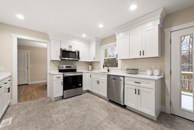 kitchen with appliances with stainless steel finishes, sink, and white cabinets