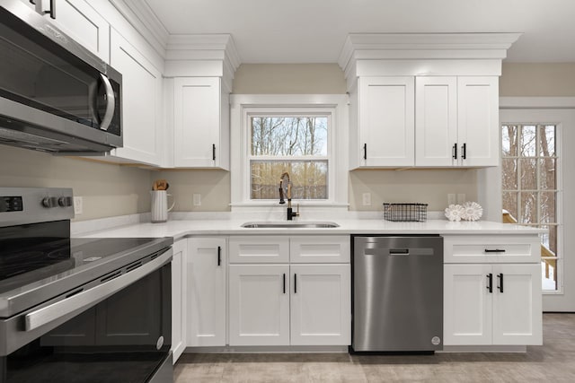 kitchen with white cabinetry, appliances with stainless steel finishes, sink, and a healthy amount of sunlight