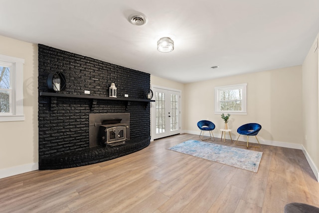 workout room with french doors, hardwood / wood-style floors, and a wood stove