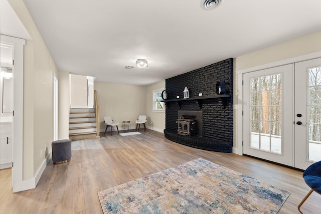 living room featuring a wood stove, light wood-type flooring, and french doors