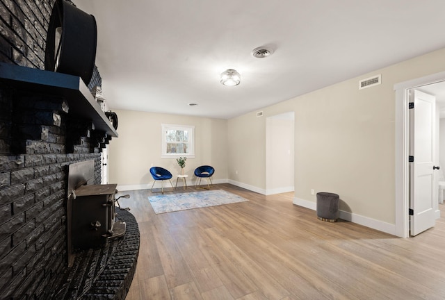 workout area featuring a brick fireplace and light hardwood / wood-style floors