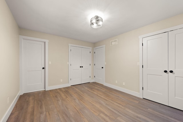 unfurnished bedroom featuring light hardwood / wood-style floors and multiple closets