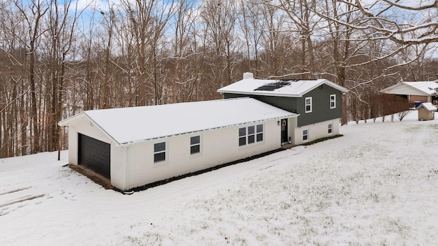 snow covered back of property with a garage