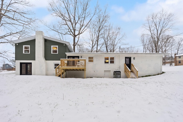 snow covered property featuring central AC unit and a wooden deck