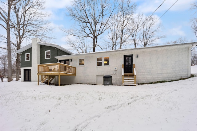 snow covered back of property with a deck