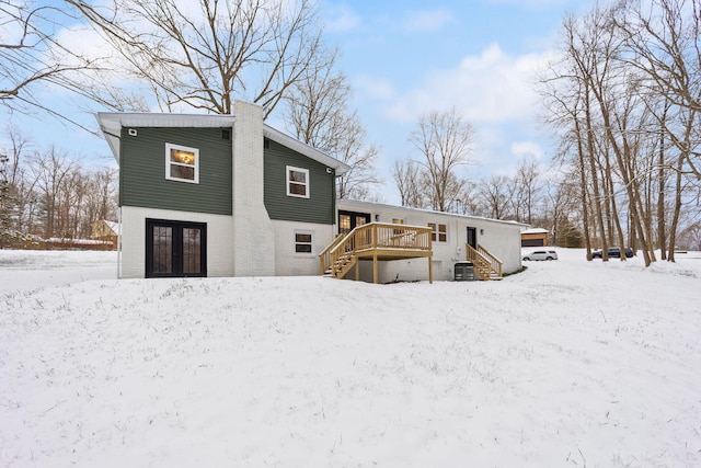 snow covered property featuring central AC, french doors, and a deck