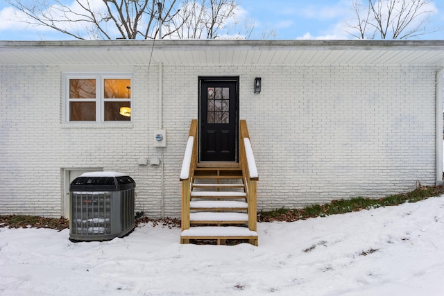 snow covered property entrance featuring cooling unit