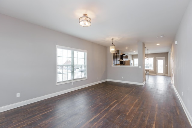 unfurnished living room featuring dark hardwood / wood-style floors and an inviting chandelier