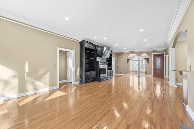 unfurnished living room featuring ornate columns, a fireplace, light wood-type flooring, and ornamental molding