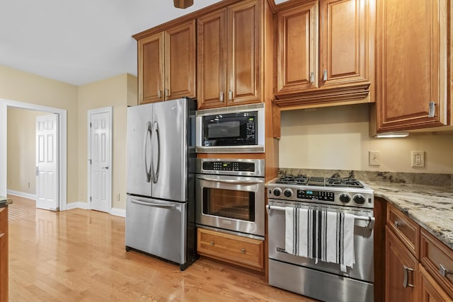 kitchen featuring light stone counters, light hardwood / wood-style flooring, and appliances with stainless steel finishes