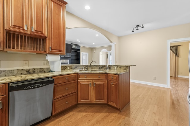 kitchen with sink, light stone counters, light hardwood / wood-style flooring, stainless steel dishwasher, and kitchen peninsula