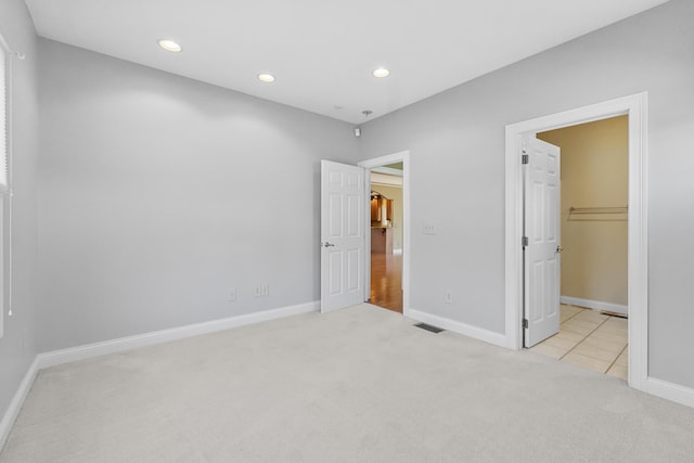 unfurnished bedroom featuring light carpet, a closet, and a spacious closet