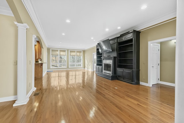 unfurnished living room with a fireplace, light hardwood / wood-style flooring, ornate columns, and ornamental molding