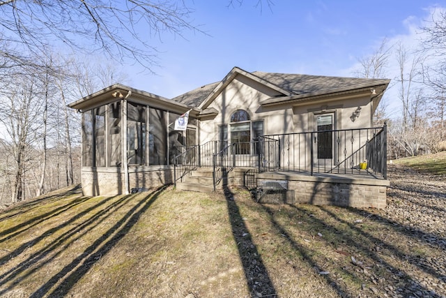 view of front of home featuring a sunroom and a front lawn