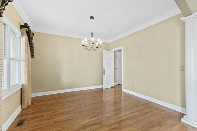 interior space with hardwood / wood-style flooring, an inviting chandelier, ornamental molding, and ornate columns