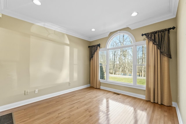 spare room with crown molding, a wealth of natural light, and light hardwood / wood-style flooring