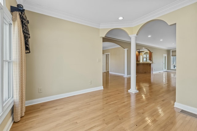 unfurnished room with light hardwood / wood-style flooring, ornate columns, and crown molding