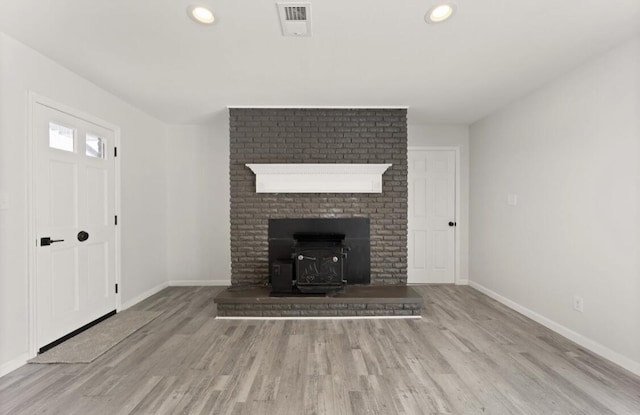 unfurnished living room with a wood stove and light wood-type flooring