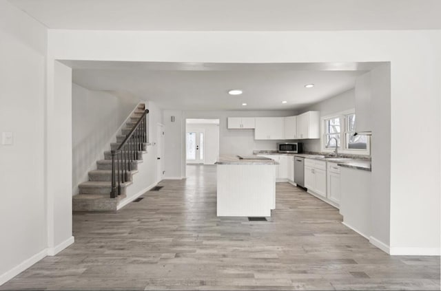 kitchen featuring sink, white cabinetry, light hardwood / wood-style flooring, appliances with stainless steel finishes, and a kitchen island