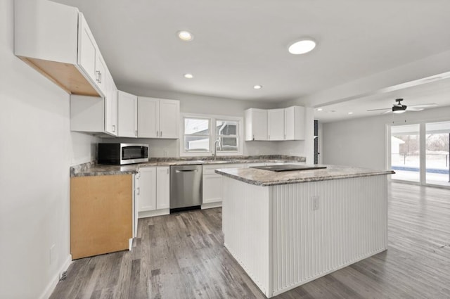 kitchen with sink, white cabinetry, a kitchen island, stainless steel appliances, and light hardwood / wood-style floors