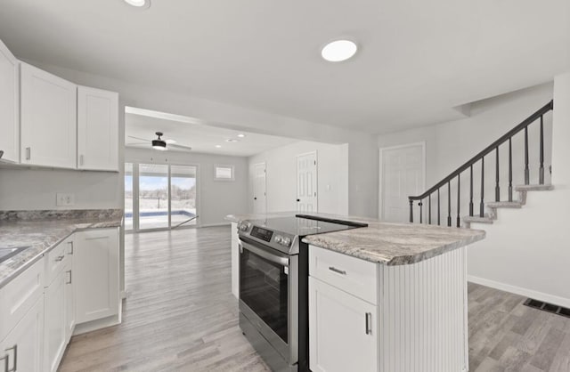 kitchen with light hardwood / wood-style floors, stainless steel range with electric cooktop, and white cabinets