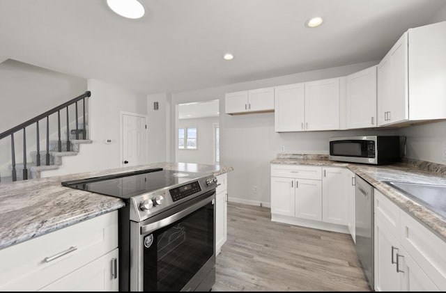 kitchen featuring stainless steel appliances, light stone countertops, light wood-type flooring, and white cabinets