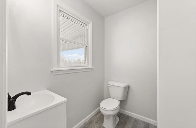 bathroom featuring wood-type flooring, toilet, and vanity