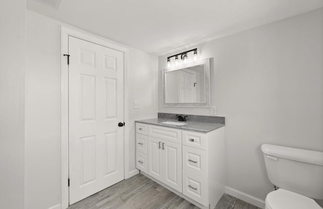 bathroom with wood-type flooring, vanity, and toilet