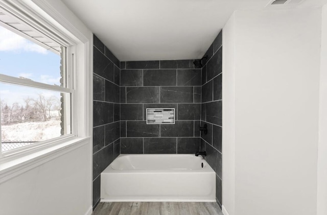 bathroom featuring tiled shower / bath combo and hardwood / wood-style flooring