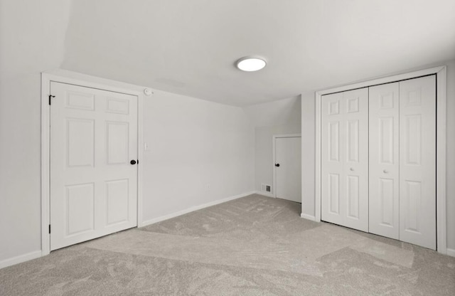 unfurnished bedroom featuring vaulted ceiling, light colored carpet, and a closet