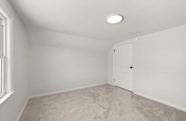 additional living space with lofted ceiling and light carpet