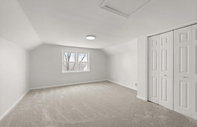 bonus room with vaulted ceiling and light carpet