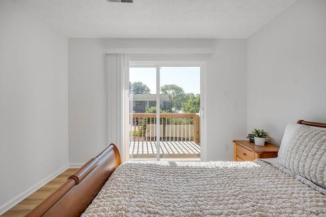 bedroom featuring hardwood / wood-style floors, a textured ceiling, and access to outside