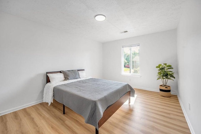 bedroom with light hardwood / wood-style floors and a textured ceiling