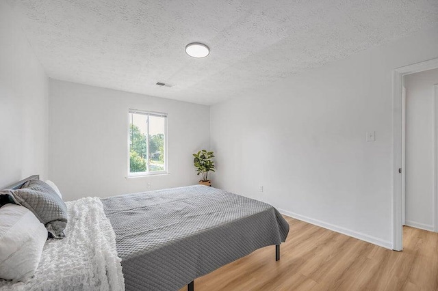 bedroom with hardwood / wood-style floors and a textured ceiling