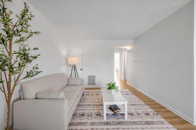 living room featuring a textured ceiling and light wood-type flooring