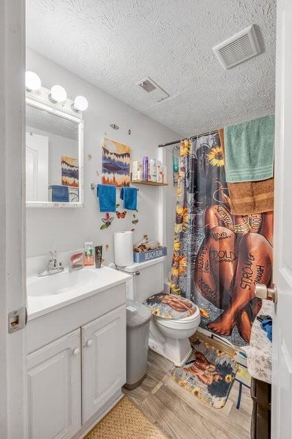 bathroom with a shower with curtain, vanity, a textured ceiling, hardwood / wood-style floors, and toilet