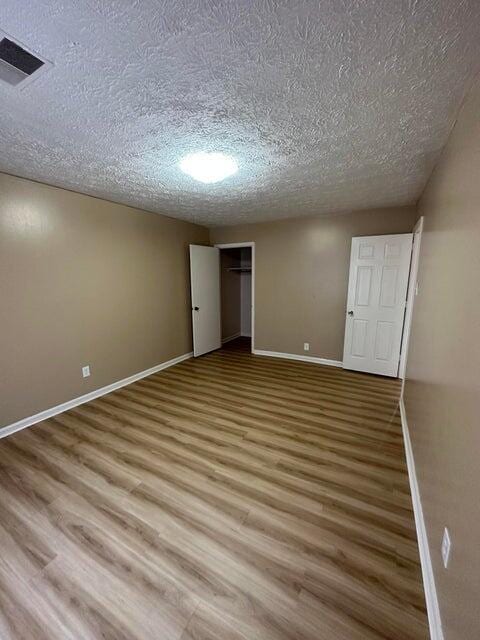 unfurnished bedroom featuring a closet, hardwood / wood-style floors, and a textured ceiling