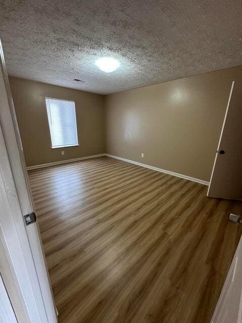 spare room featuring hardwood / wood-style flooring and a textured ceiling