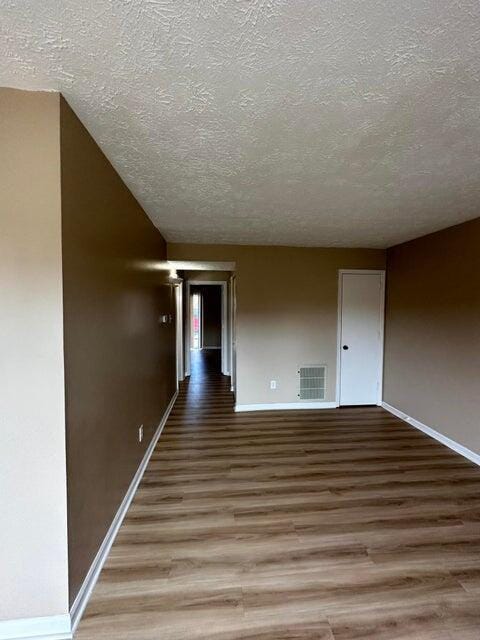 unfurnished room featuring wood-type flooring and a textured ceiling