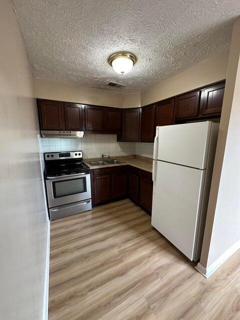 kitchen featuring electric stove, sink, light wood-type flooring, and white refrigerator