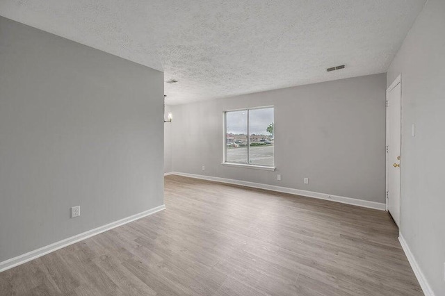 empty room with wood-type flooring and a textured ceiling